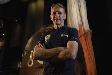 Astronaut Tim Peake stands in front of his Soyuz space capsule