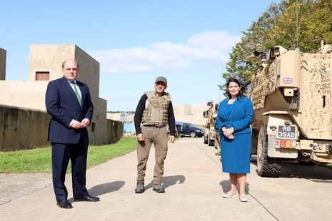 A serving person in full uniform standing next to Ben Wallace and Priti Patel. 