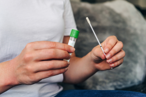 Person holding testing swab and container