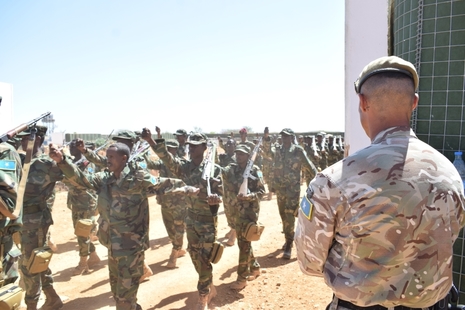 Somali soldiers march past a UK instructor during their training graduation ceremony