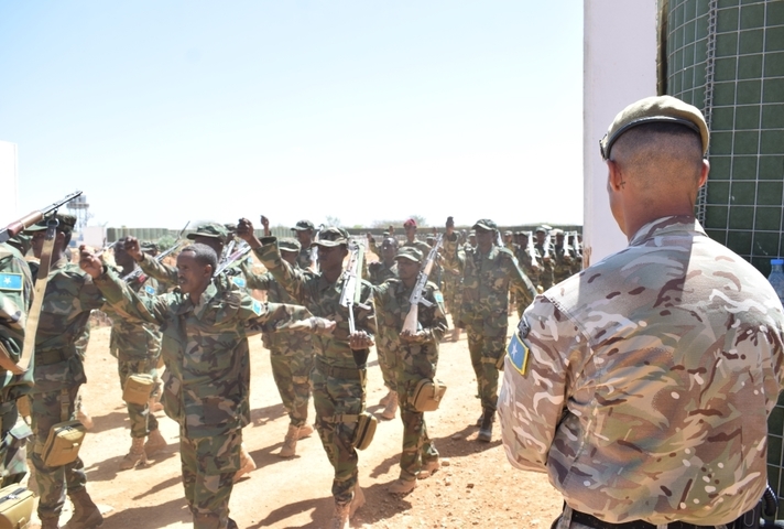 Somali soldiers march past a UK instructor during their training graduation ceremony