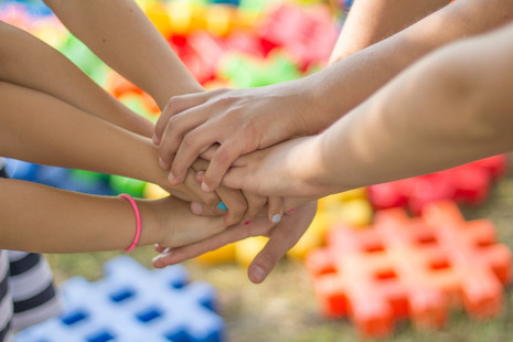 Friends in a circle put their hands in the middle