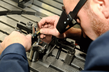 An engineer adjusts a component on a work bench.