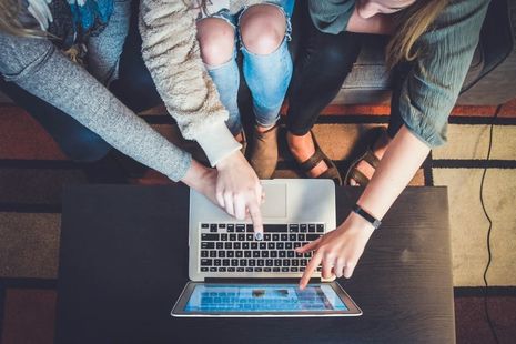 Image of young people pointing at laptop.