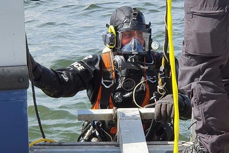 Diver emerging from water and climbing onto boat