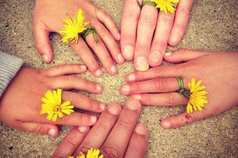 Circle of hands with dandelions on their fingers