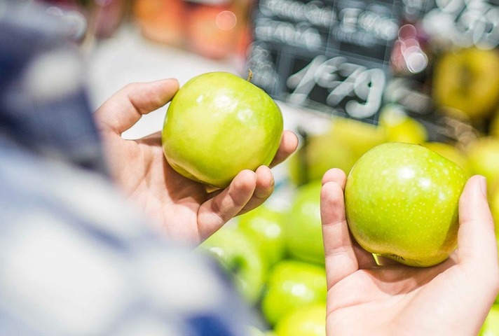 Someone comparing two green apples
