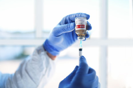 A person holding a syringe and a vial containing a COVID-19 vaccine