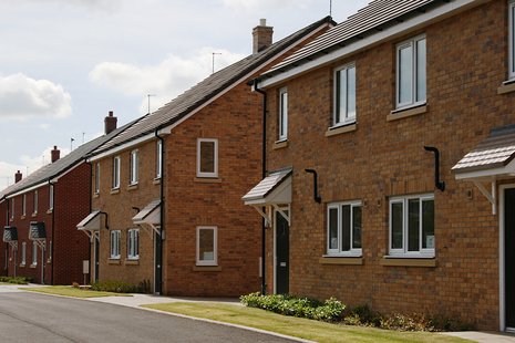 A row of new semi-detached brick houses with small front lawns.