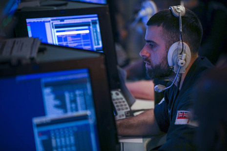 Image depicts sailor working in an operations room.
