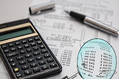 Image of calculator, pen, magnifying glass and sheet with figures