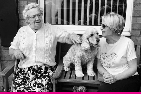 Picture of two women having a conversation on a bench with a dog between them