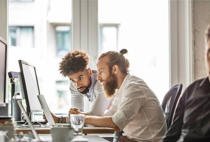 Two men in an office looking at a computer screen. Image: Getty
