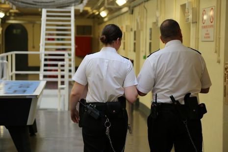 Женщины и мужчины-сотрудники тюрьмы ходят