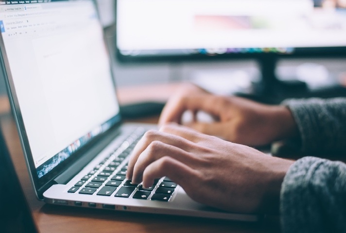 Hands typing on laptop keyboard.
