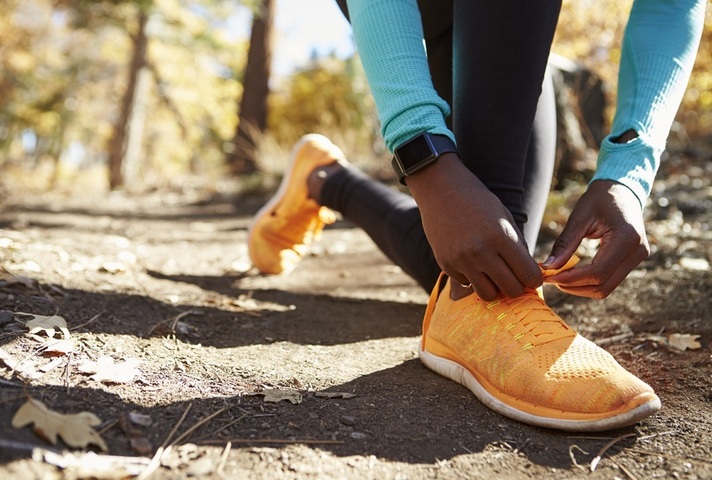 Close up of runner tying shoes, wearing fitness tracker