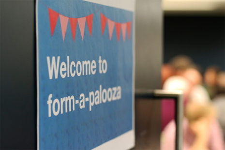 Paper “Welcome to form-a-palooza” sign on a door to a room full of people.