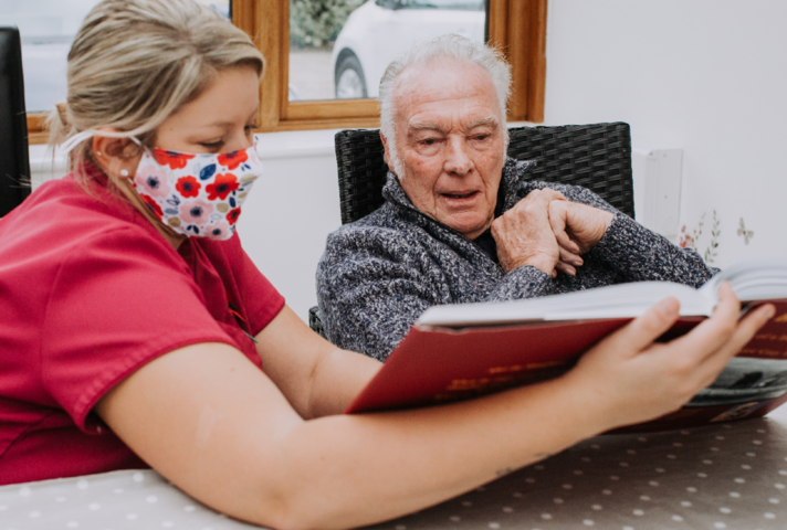 Care worker and older man looking a a book