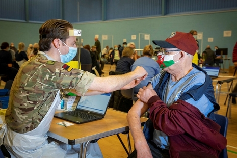An Armed Forces member administers a vaccine in Wales earlier this year