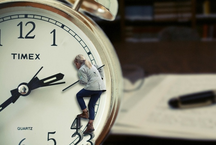 Woman climbing on clockface with blurred background image of desk and notepad in study