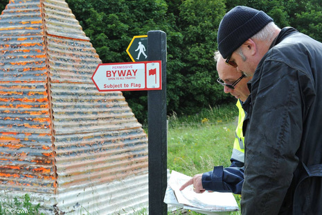 Two men looking at paper work next to rights of way signs on Salisbury Plain Training Area
