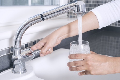 Person filling a glass with drinking water from the tap.