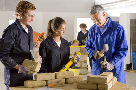 An instructor shows a male and female apprentices building and construction work.