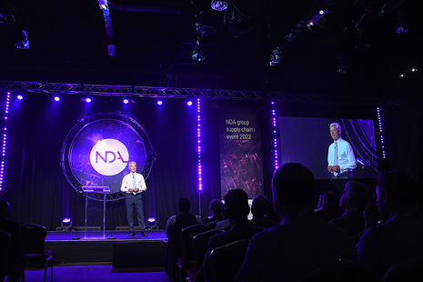 NDA group CEO, David Peattie, speaking on stage at the event with purple lighting