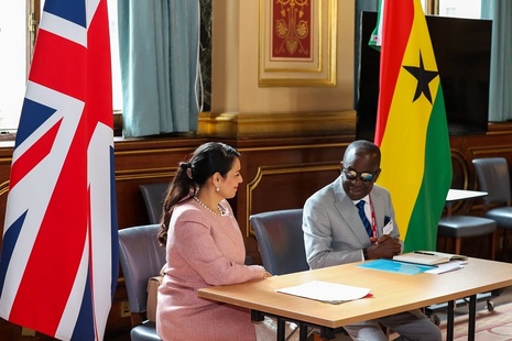 UK Home Secretary Priti Patel and the Minister for National Security of Ghana Kan-Dapaah seated at a desk between the UK and Ghanaian flags.