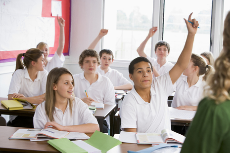 classroom of students with hands raised