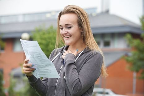 teenage girl smiling and looking at her exam results