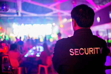 Image shows a security operative watching over people