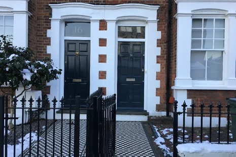 Front doors of two Victorian houses with black and white tiled pathways.
