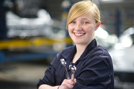 female apprentice wearing overalls and holding a spanner