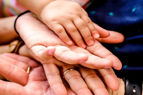 Adult and child hands placed on top of one another