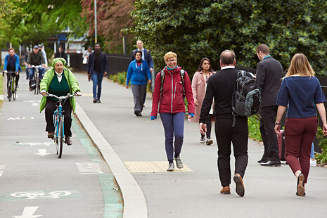 Люди ездят на велосипеде и идут рядом друг с другом