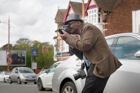 Photographer Vanley Burke looks through his camera on a residential street in Birmingham. © Harry Zundel, TMAX
