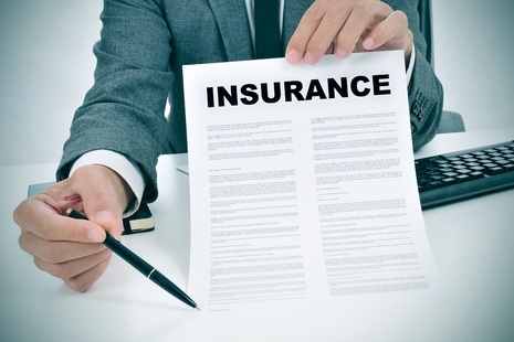 Man wearing suit holds letter towards viewer. The headline 'Insurance' is clear and the words on the rest of the document are unclear.