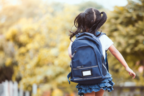 A young child wearing a school backpack is running