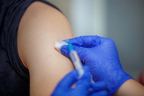 A close-up of a health professional injecting a person's arm