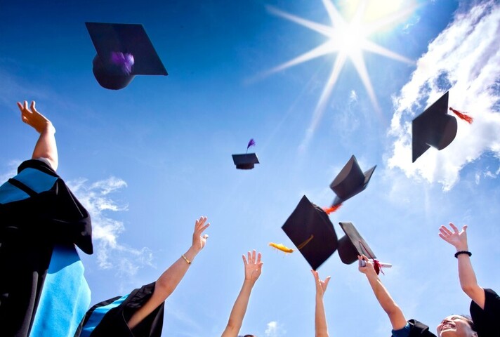 Студенты бросают в воздух свои выпускные шапки