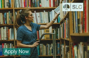 Woman looking at books in a Library with the words - Apply Now