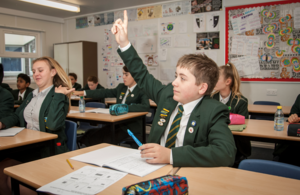 Secondary school student raising his hand in class