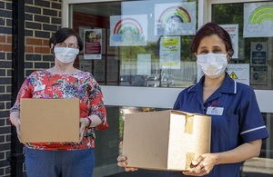 Social care workers wearing face masks and carrying boxes