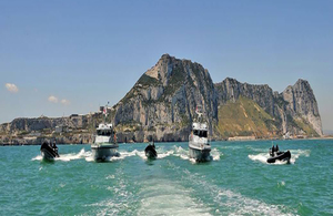 Two boats in front of a large rock formation in Gibraltar.