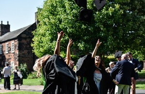 Image of graduating project academy students throwing hats off in the air