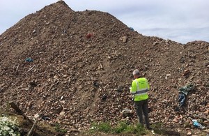 Environment Agency Officer in front of a large waste pile