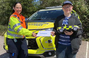 Traffic officer Angela Fenne hands the invitation to Toby for a future ride-out in a Highways England TOV during a socially-distanced meeting at the M5 Exeter Services