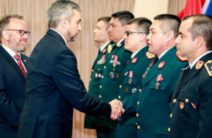 Presiente Mario Abdo at the center shaking hands with one of the RMAS graduates, in line with his peers who await their turn. Ambassador Hedges is accompanying behind President Abdo.