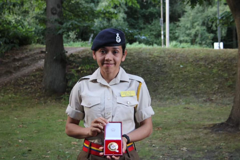 Officer Cadet Susy Benítez Giménez stands before the camera displaying the King Hussain award.